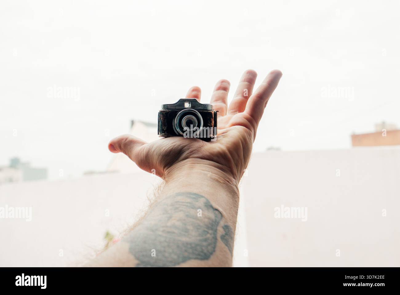 Die Hand hält eine winzige Retro-Kamera und zeigt neue Fotokonzepte Stockfoto