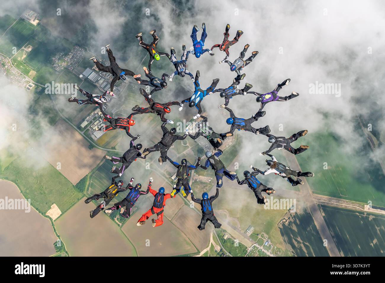 Eine große Gruppe von Fallschirmspringern baut eine komplexe Freifallformation hoch über der britischen Landschaft während einer sequenziellen Fallschirmspringerrekordzeit Stockfoto