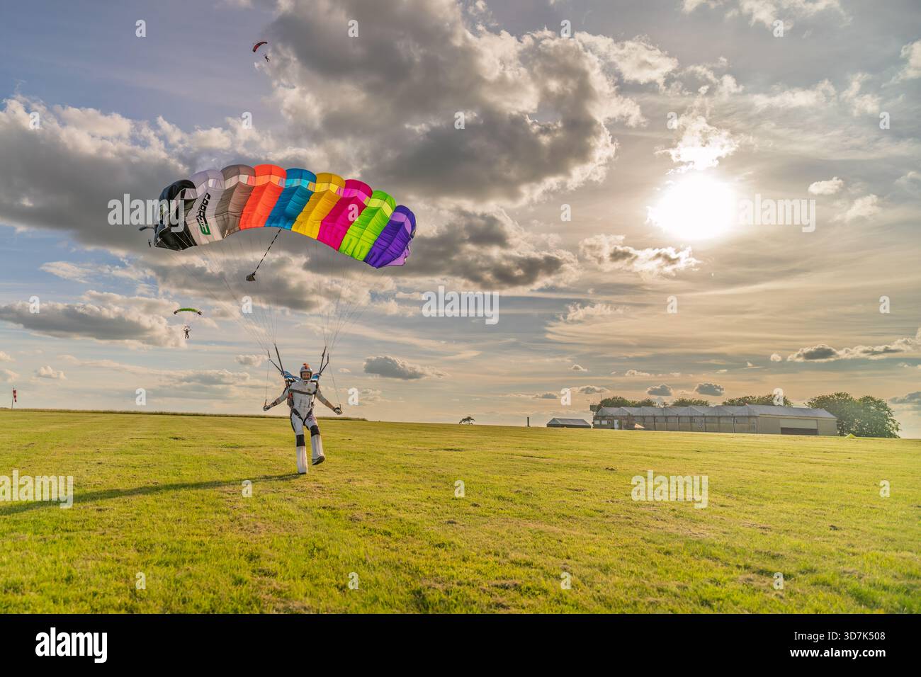 Fallschirmspringer landet Regenbogenfallschirm auf einem Feld Stockfoto