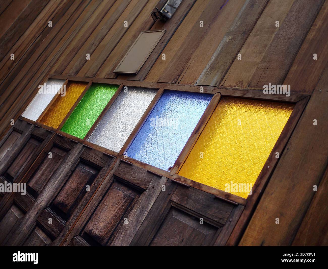 Vintage-Architekturdetails. Flacher perspektivischer Blick auf eine traditionelle Holzwand mit einer Reihe von bunten gemusterten Glasfenstern (grün, Stockfoto