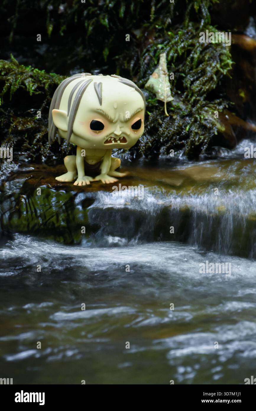 Funko Pop Actionfigur von Gollum aus dem Fantasy-Film der Herr der Ringe. Moosige, feuchte Steine, schaumiges Wasser des Baches. Stockfoto