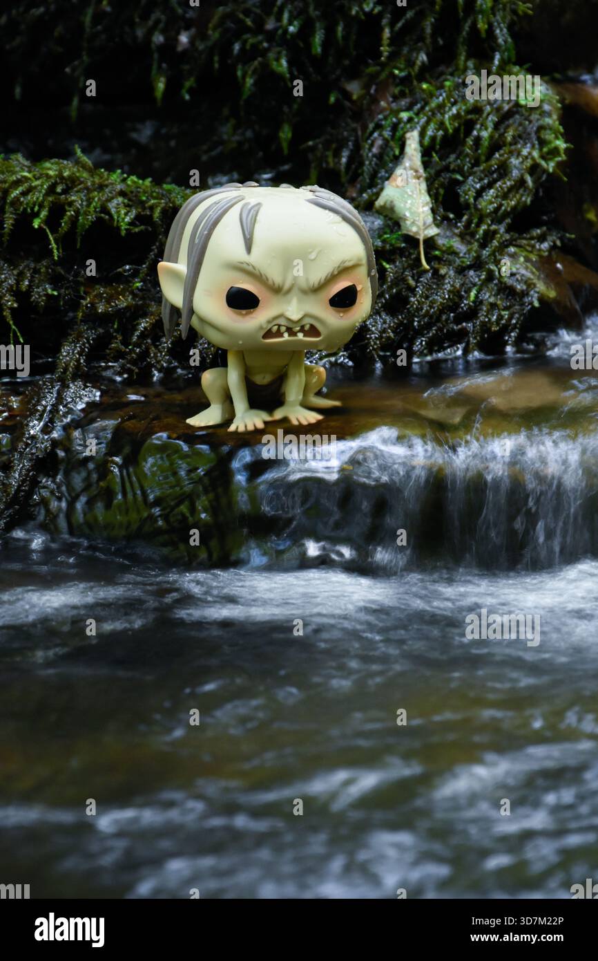 Funko Pop Actionfigur von Gollum aus dem Fantasy-Film der Herr der Ringe. Moosige, feuchte Steine, schaumiges Wasser des Baches. Stockfoto