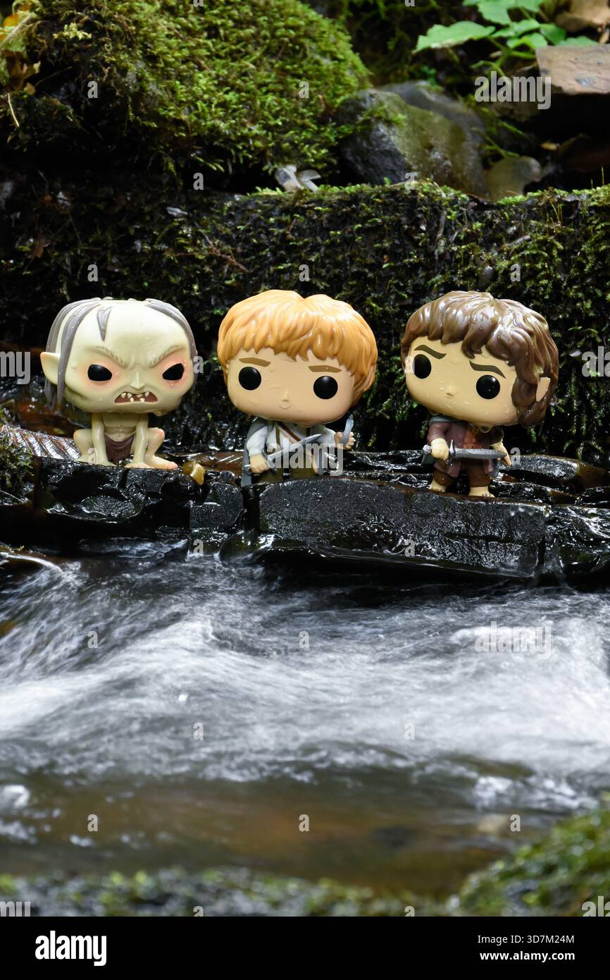 Funko Pop Actionfiguren von Gollum, Sam und Frodo aus dem Film der Herr der Ringe. Moosige, feuchte Steine, schaumiges Wasser. Stockfoto