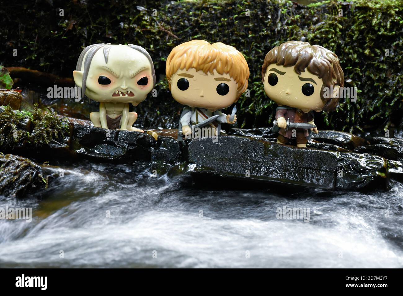 Funko Pop Actionfiguren von Gollum, Sam und Frodo aus dem Film der Herr der Ringe. Moosige, feuchte Steine, schaumiges Wasser. Stockfoto