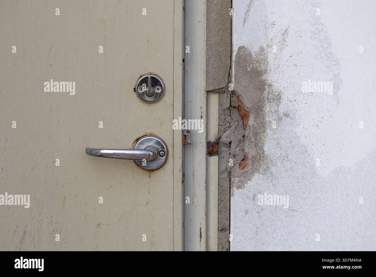 Nahaufnahme einer neuen Stahltür mit einem modernen Türhebelsatz und einem freiliegenden mechanischen Türschlosszylinder (Schlüsselzylinder, Schließkern). Un Stockfoto