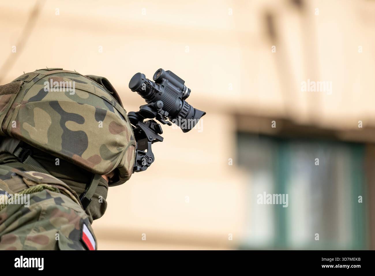 Polnischer Infanterie-Soldat mit helmmontierter Nachtsichtbrille, getarnter Uniform und Gesichtsmaske, seitliche Nahaufnahme vor verschwommenem urbanem Hintergrund Stockfoto