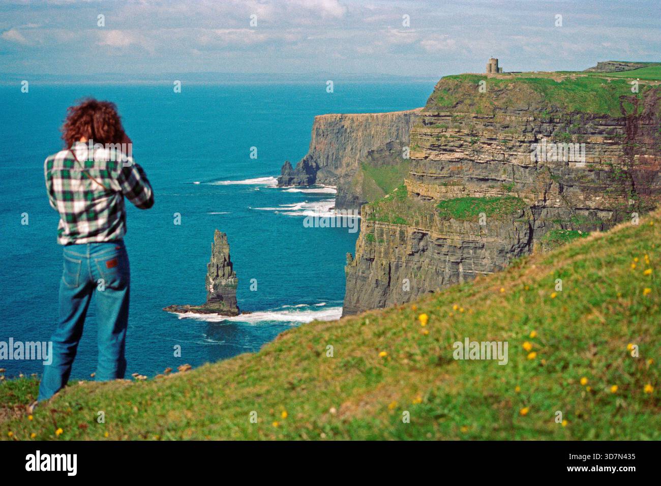 Junger Mann, der Fotos am Rande der Klippen macht, es gab noch keinen Zaun, Cliffs of Moher, County Clare, Republik Irland, 08. September, 1990 Stockfoto