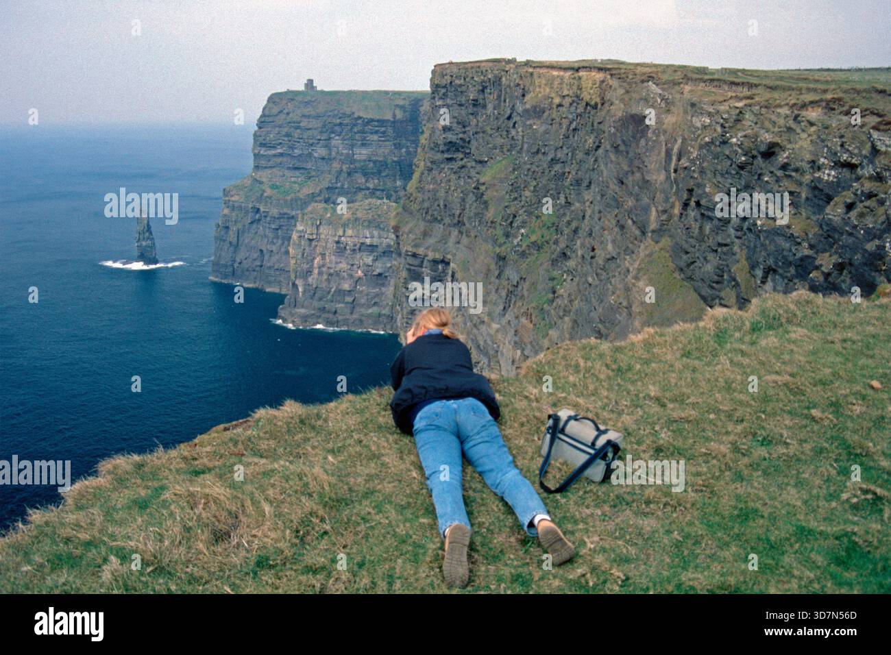 Junge Frau, die Fotos am Rande der Klippen macht, es gab noch keinen Zaun, Cliffs of Moher, County Clare, Republik Irland, April 1996 Stockfoto
