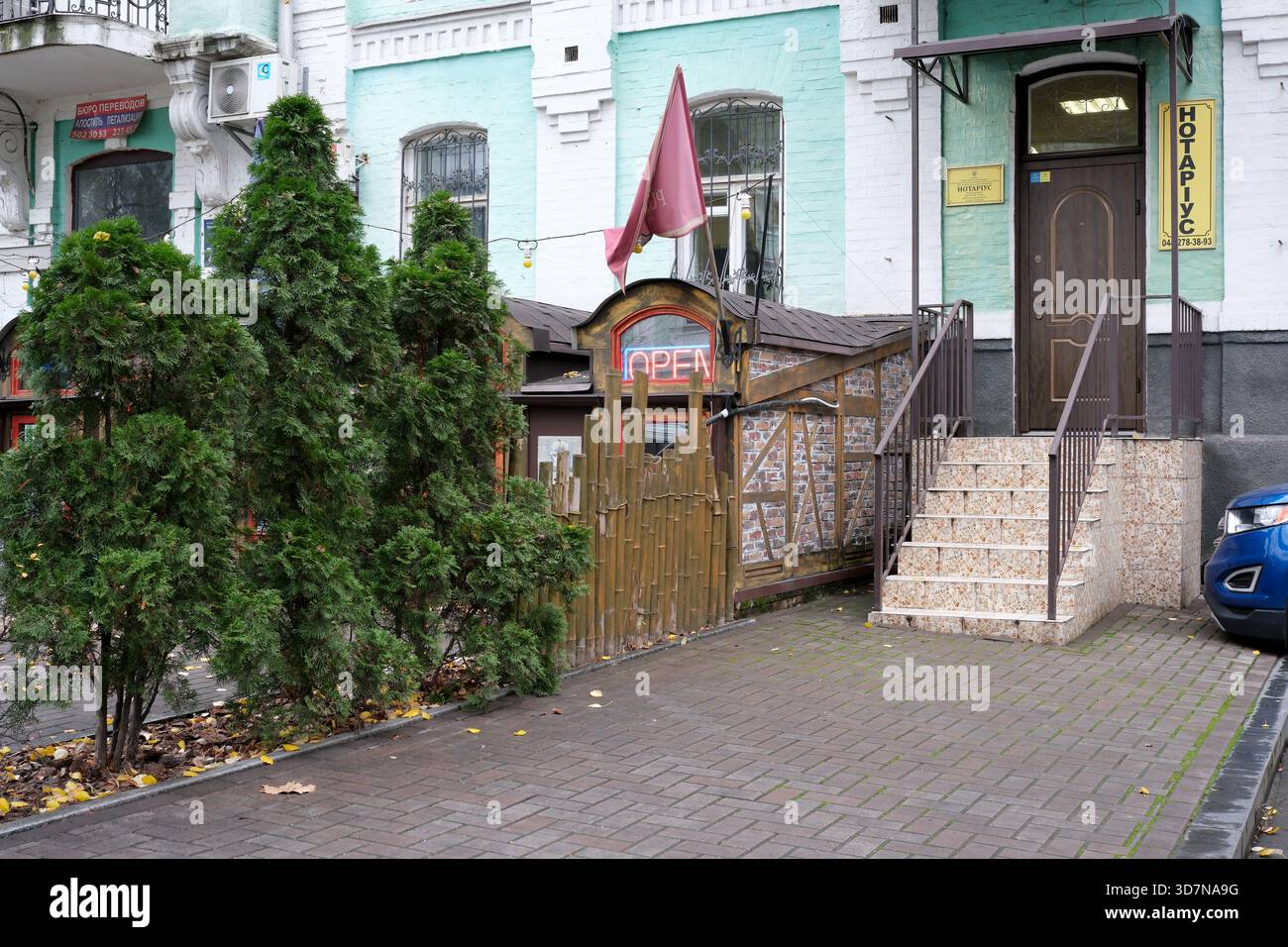 Ein gemütliches Restaurant empfängt Gäste mit lebendigen Pflanzen und einem einladenden offenen Schild. Kiew, Ukraine, 26. November 2025. Stockfoto