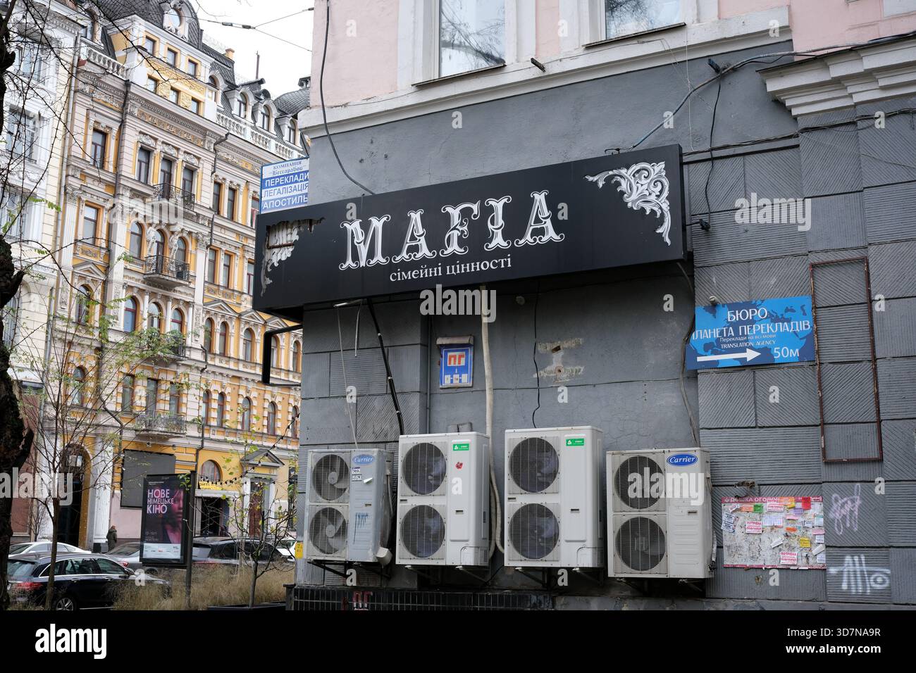 Ein Schild für ein Familienrestaurant steht an einer geschäftigen Straßenecke, die von Gebäuden umgeben ist. Kiew, Ukraine, 26. November 2025. Stockfoto