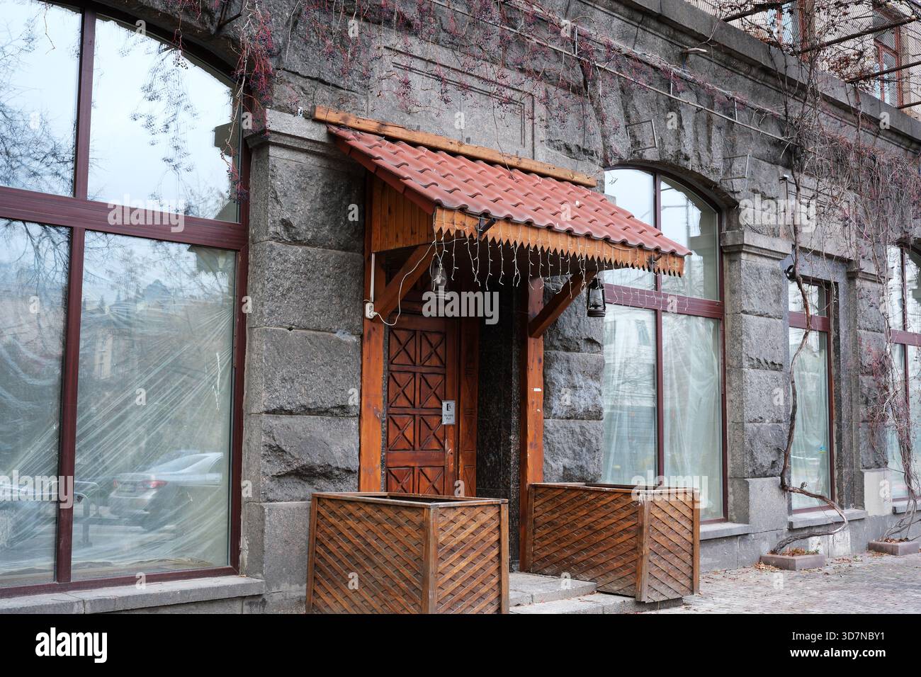 Verwitterte Steinwände umrahmen eine einladende Holztür, die auf gemütliche Erlebnisse hindeutet. Kiew, Ukraine. November 2025. Stockfoto