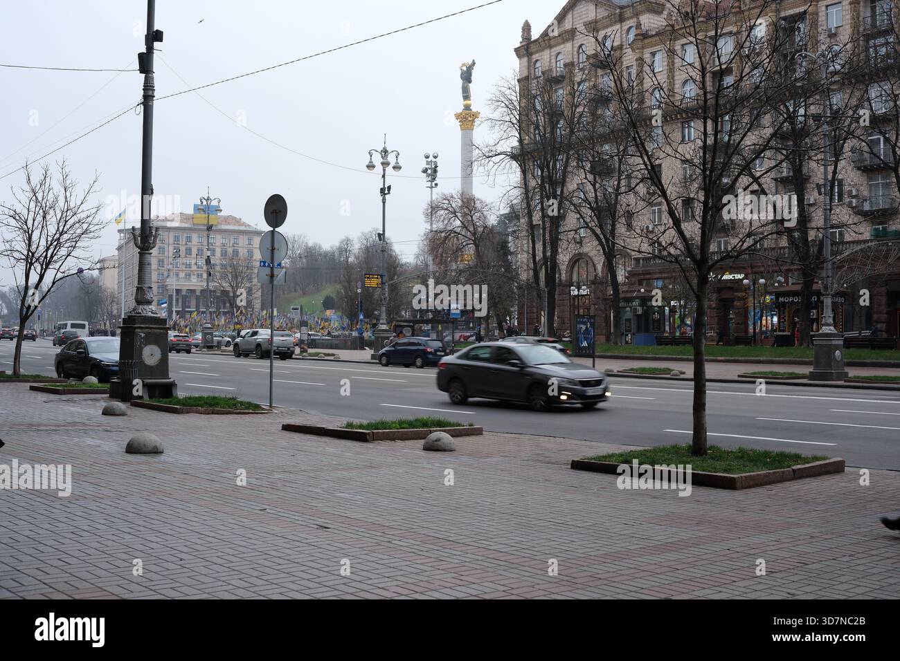 Autos fahren durch eine geschäftige Straße mit Gebäuden unter grauem Himmel. Chreshtschatjk, Kiew, Ukraine. November 2025. Stockfoto