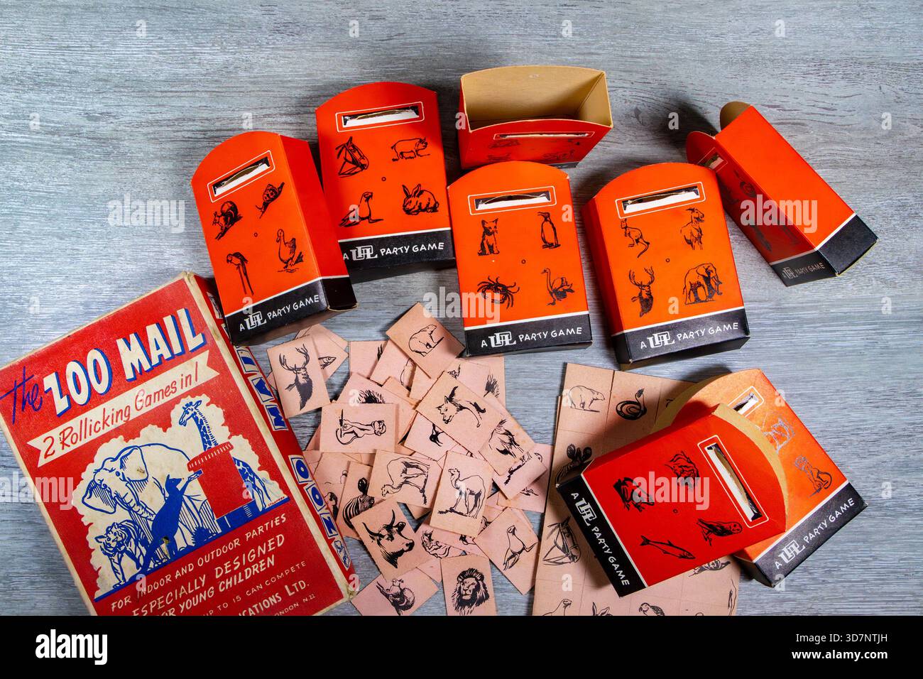 Vintage-Kinderparty-Spielset namens Zoo Mail mit roten Briefkästen und illustrierten Tierkarten auf einer Holzfläche Stockfoto