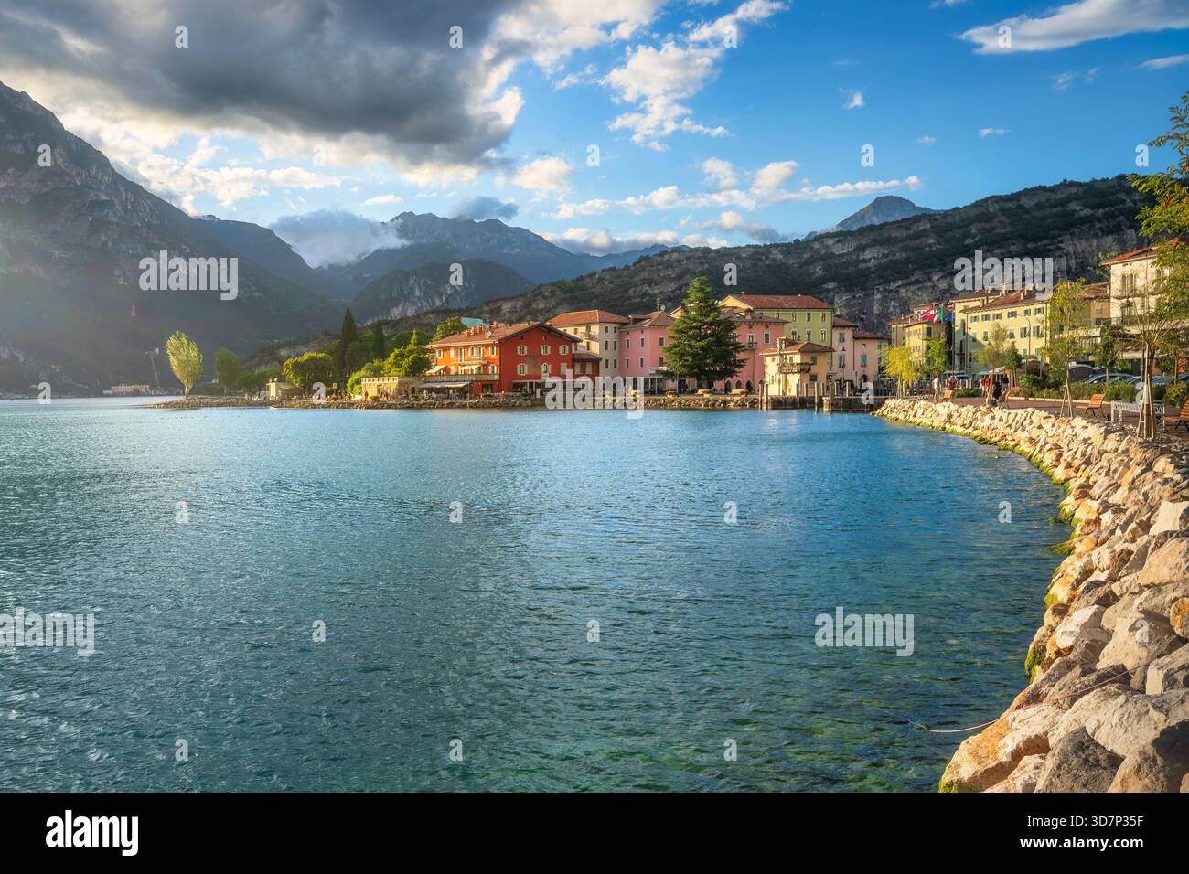 Blick auf die Ufergebäude von Torbole sul Garda, Trentino, eingebettet am Nordufer des Gardasees. Die felsige Küste wird von hohen Gipfeln eingerahmt Stockfoto