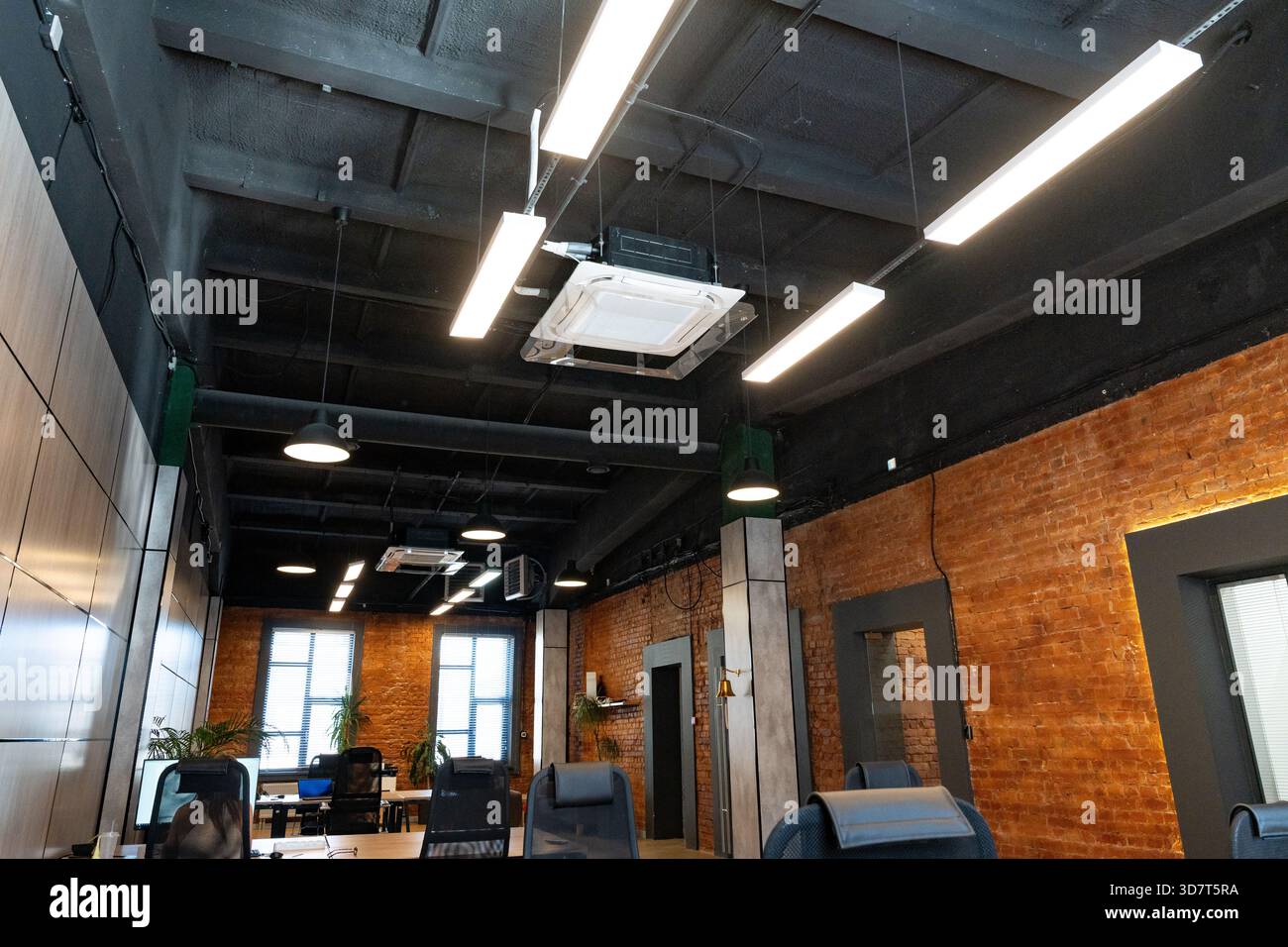 Moderne Büroeinrichtung mit industriellen Designelementen und effizienter Beleuchtung Stockfoto