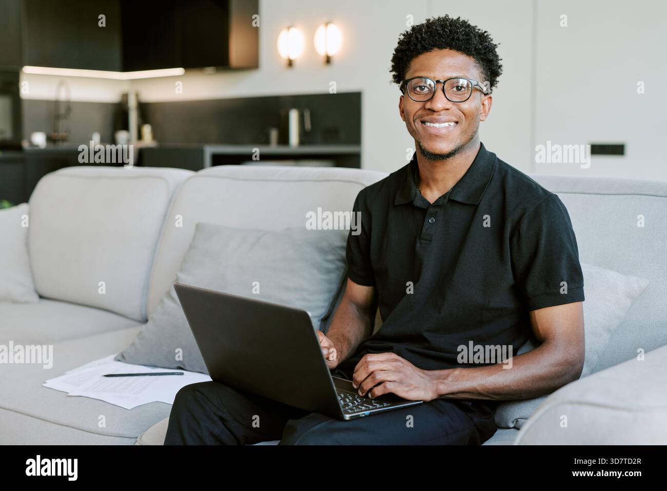 Porträt eines jungen Erwachsenen Schwarzen Mannes, der morgens beim Verwenden des Laptops lächelt Stockfoto
