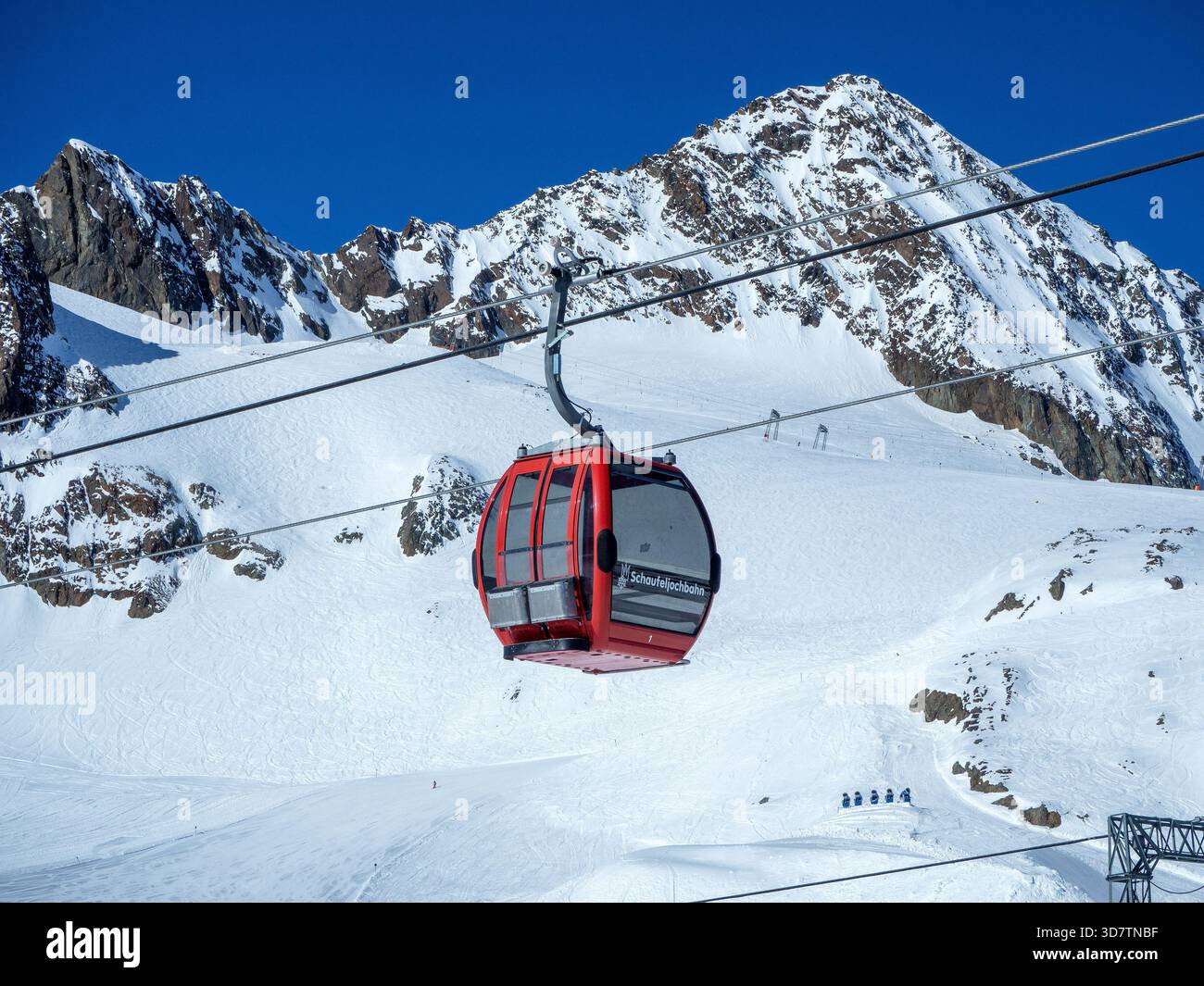 Stubai, Österreich - 7. April 2025: Rote Kabinenbahn Schaufeljochbahn im Skigebiet am Stubaier Gletscher, Schnee, Seile, Schneekanonen. Felsige Berge und Stockfoto