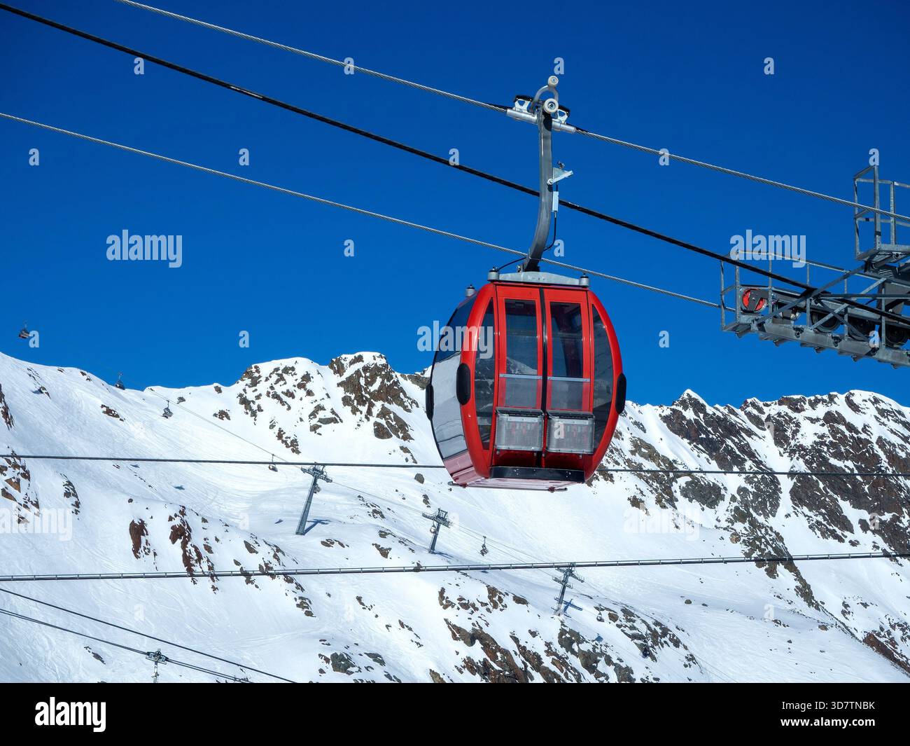 Rote Seilbahn im Skigebiet am Stubaier Gletscher, Schnee, Seile, Schneekanonen. Felsige Berge und Skilifte im Hintergrund. Skipiste unten Stockfoto