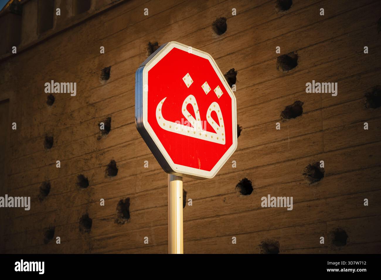 Rotes achteckiges Stoppschild mit arabischem Text an einer strukturierten Wand. Fès, Fès-Meknes, Nordmarokko Stockfoto