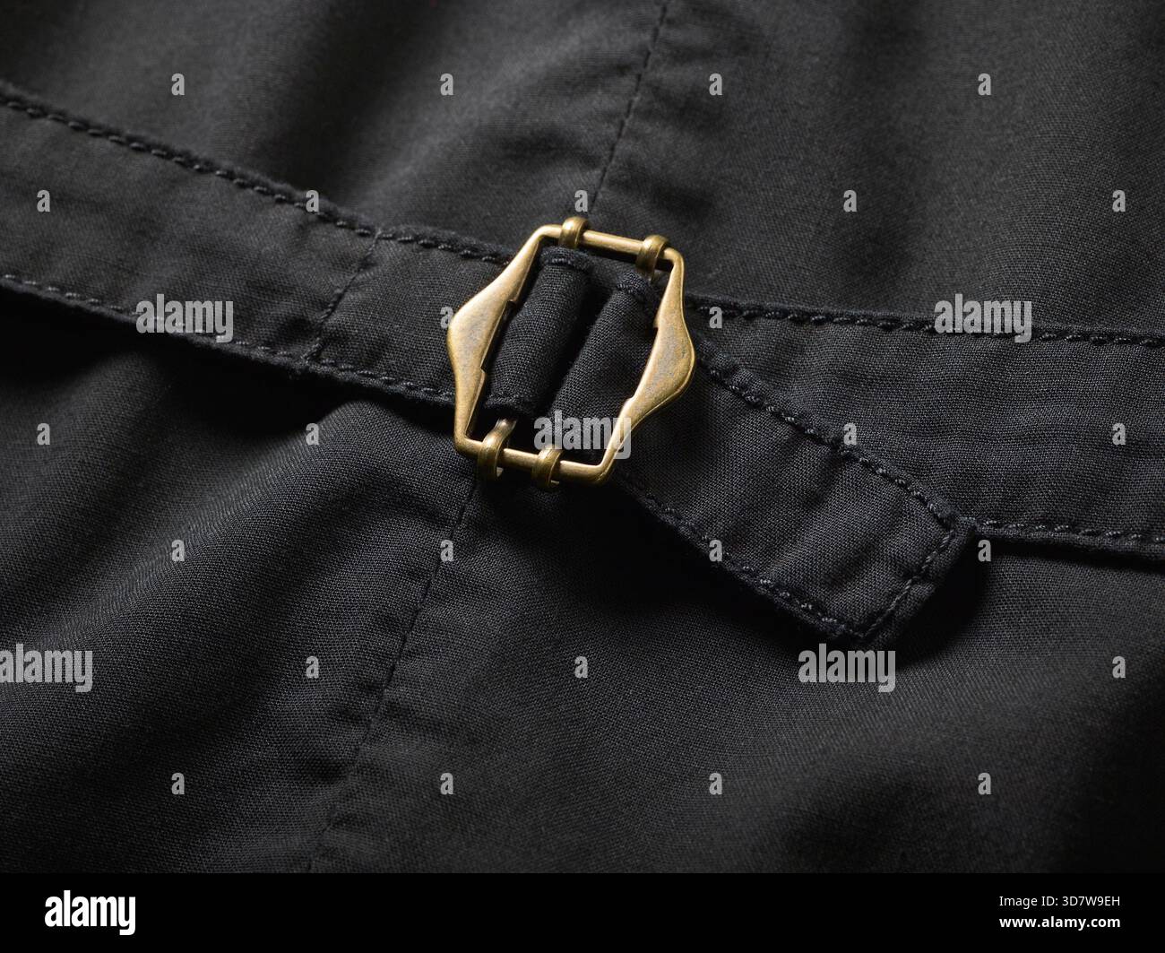 Nahaufnahme einer Messingschnalle auf dunklem Stoff mit detaillierten Nähten. Stockfoto