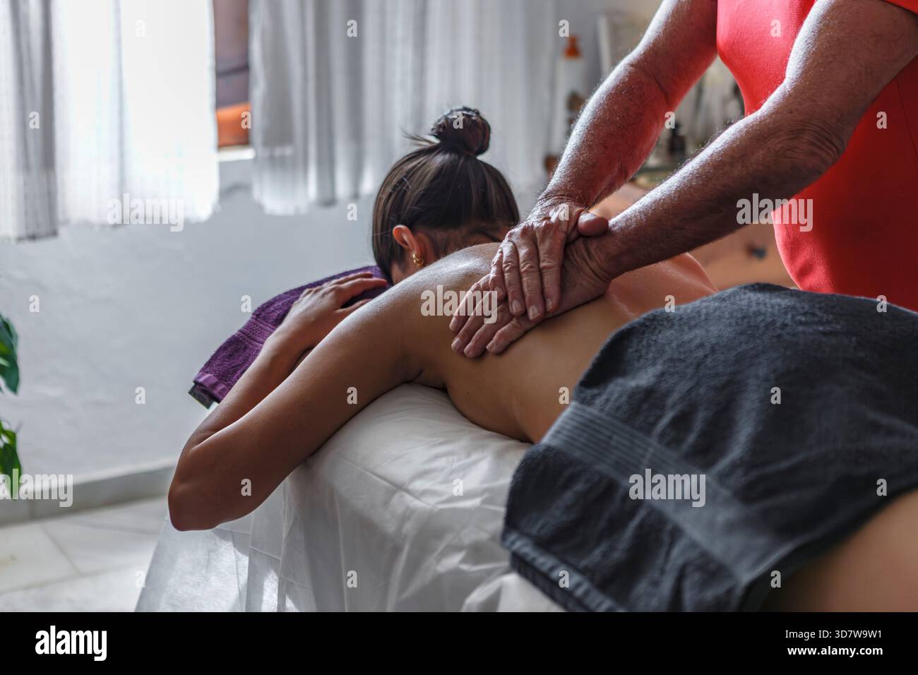 Frau, die eine Massage auf einem mit Handtüchern bedeckten Tisch in einer entspannten Umgebung erhielt. Spanien Stockfoto