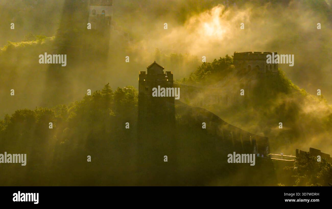 Morgennebel und Sonnenstrahlen beleuchten die alten Wachtürme der Chinesischen Mauer in Jinshanling, Provinz Hebei, China. Stockfoto