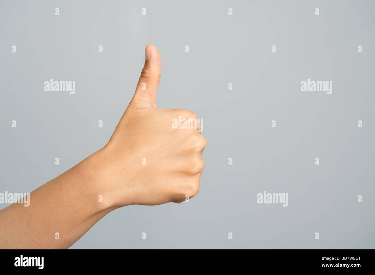 Hand zeigt Daumen nach oben Geste mit hellem Hautton vor Einem hellgrauen Studio-Hintergrund Stockfoto