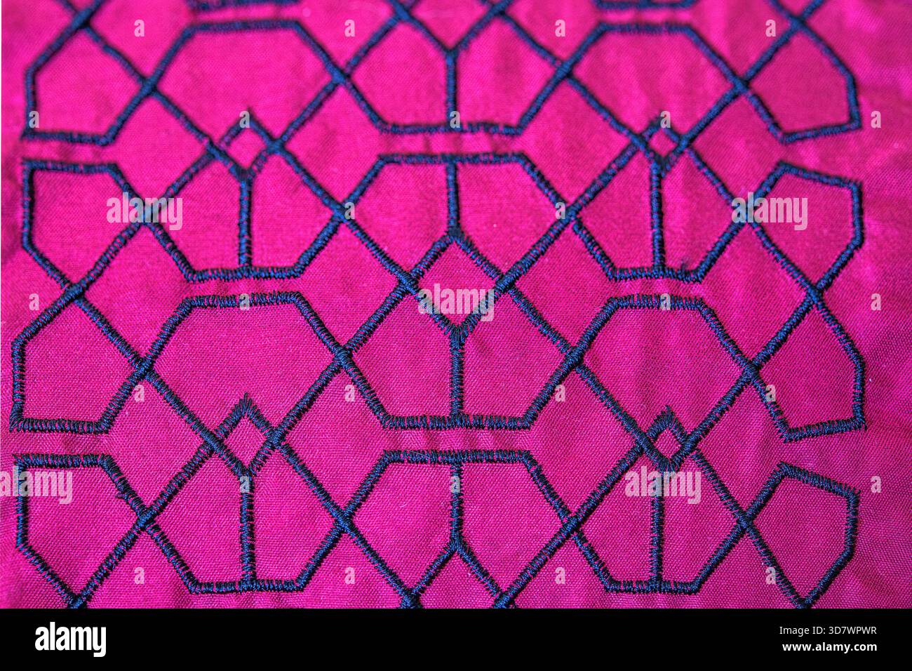 Nahaufnahme mit aufgesticktem geometrischem Muster auf hellrosa Stoff. Stockfoto