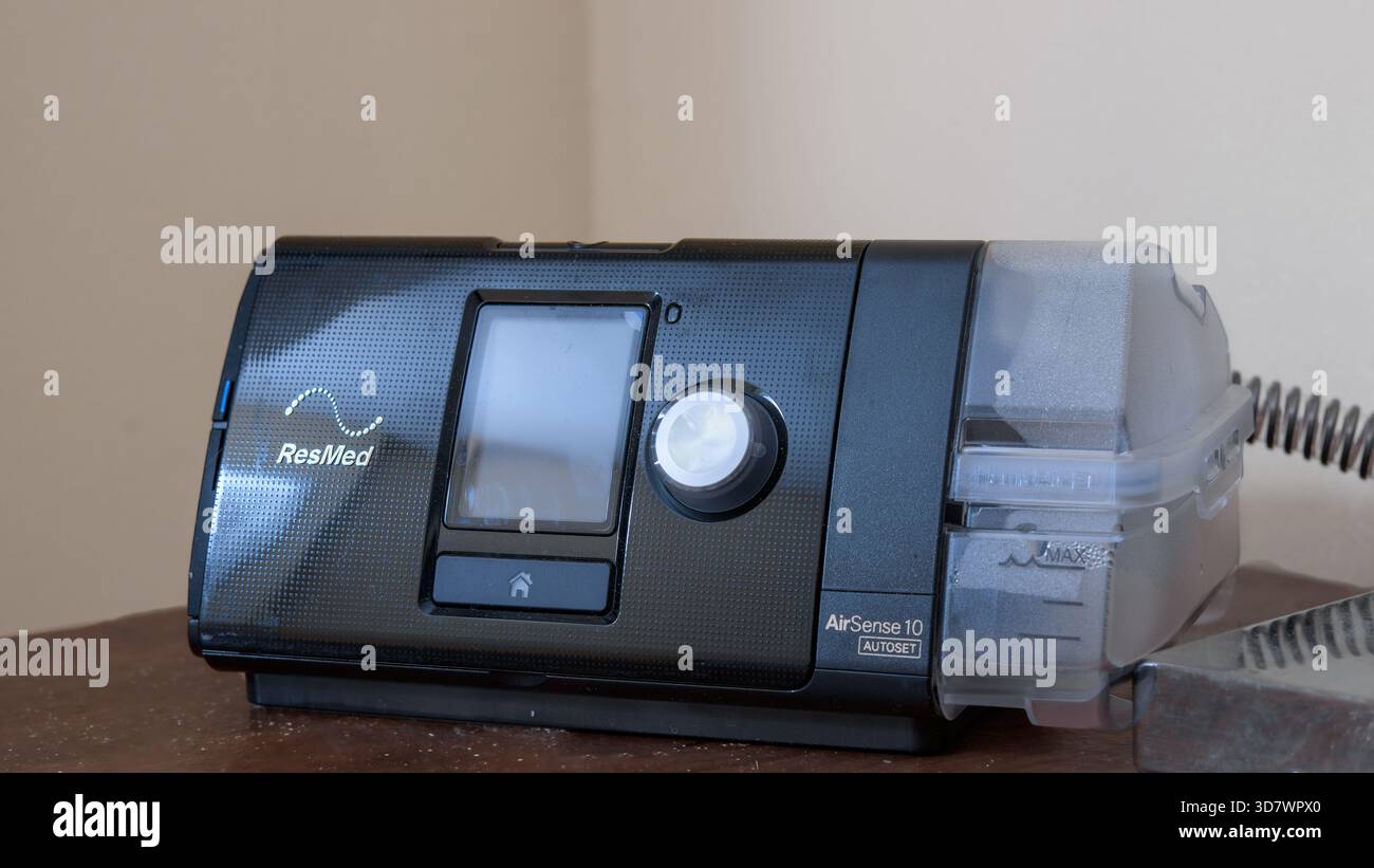 ResMed AirSense 10 CPAP-Gerät mit Luftbefeuchter auf Holzoberfläche. Stockfoto