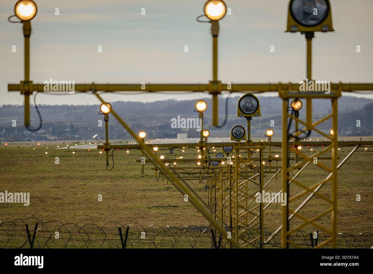 Flughafen-Anfluglichter mit der nächsten Reihe unscharf und den folgenden Reihen scharf, mit der Landebahn im Hintergrund, wodurch Tiefe und erzeugt werden Stockfoto
