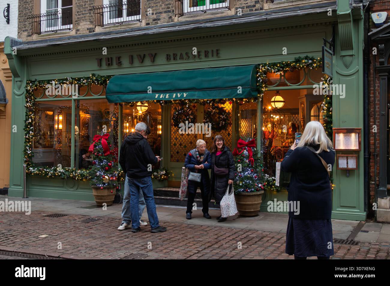 Glückliche Leute, die ihr Foto vor dem Ivy Restaurant gemacht haben, das mit Weihnachtsdekorationen bedeckt ist. Cambridge, England, Großbritannien Stockfoto