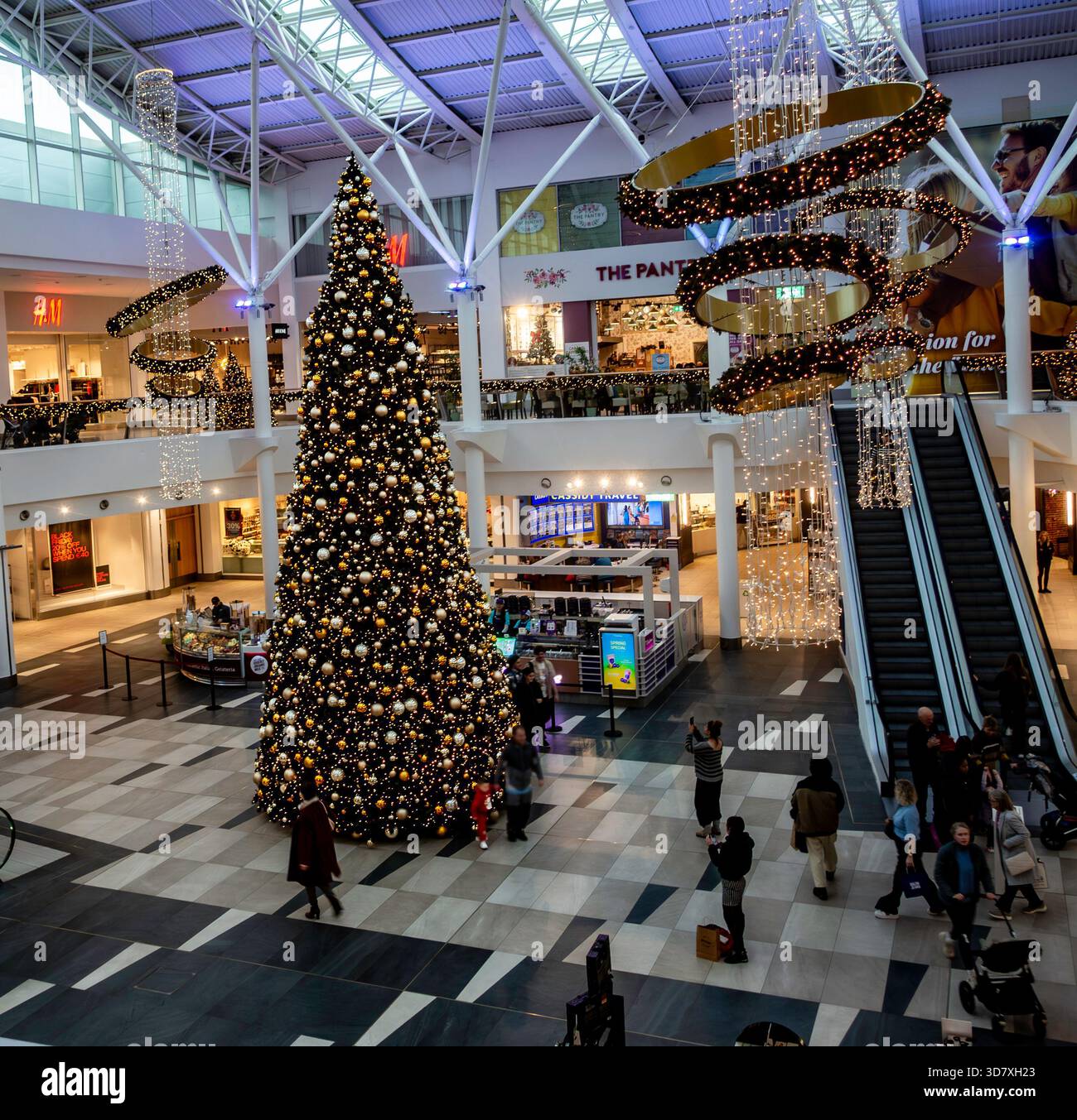 Im Atrium des Liffey Valley Shopping Centre in Dublin steht ein riesiger, dekorierter Weihnachtsbaum. Umgeben von Lichtern fängt es den Urlaub des irischen Einkaufszentrums ein Stockfoto