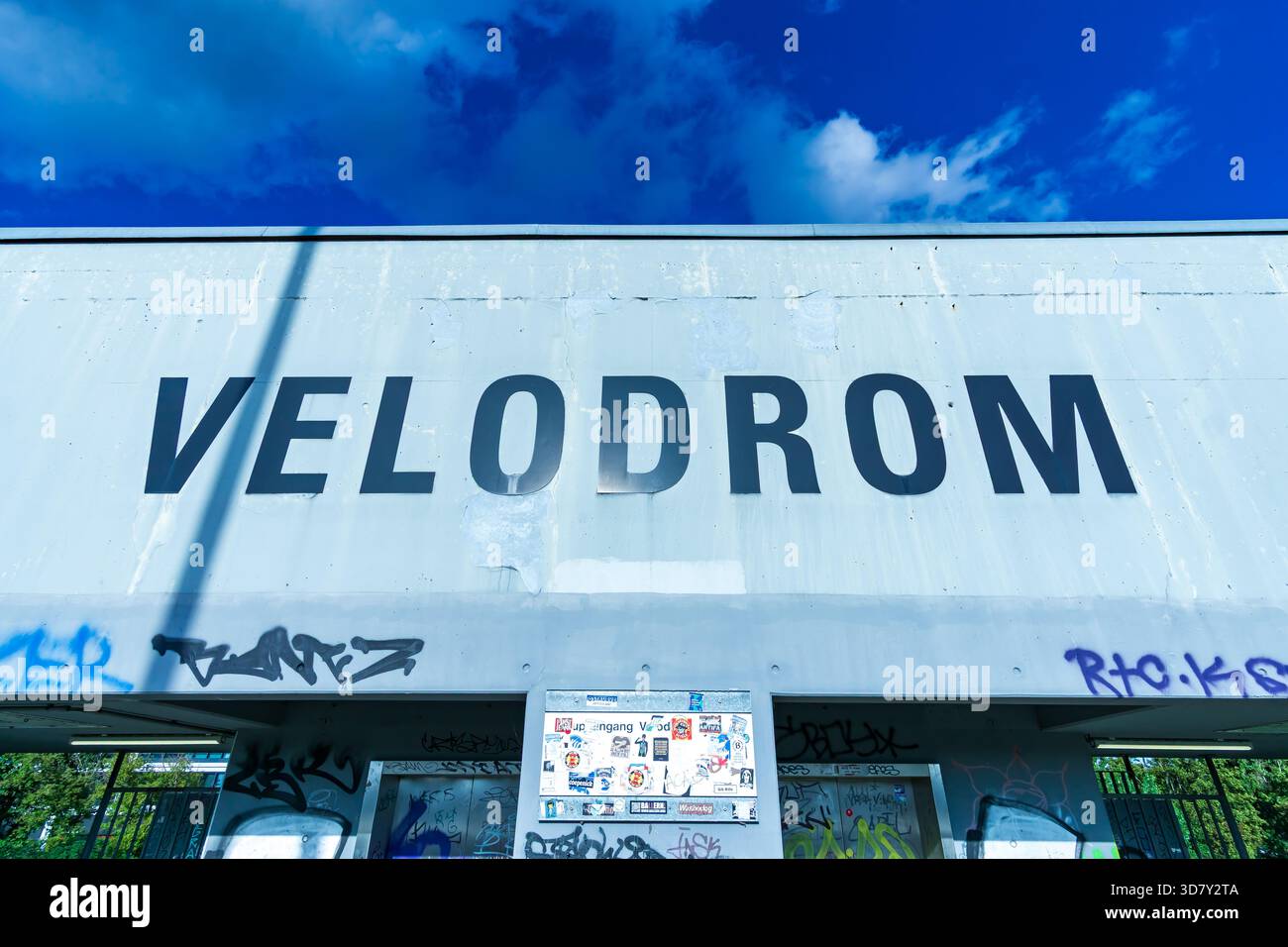 Nahaufnahme des Velodrom-Eingangs in Berlin mit Schwerpunkt auf der großen Fassadenbeschriftung und umgebenden Graffiti. Stockfoto