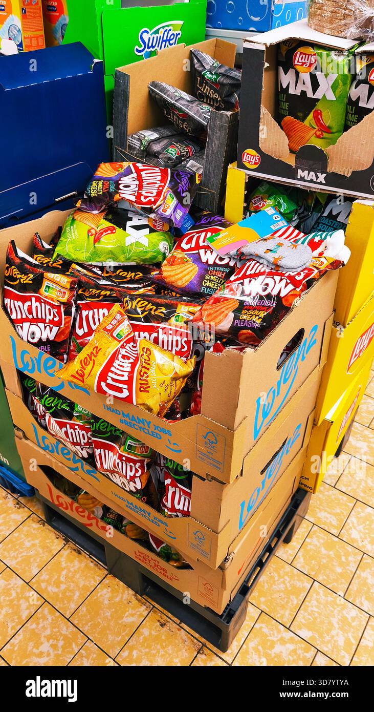 ISERLOHN, DEUTSCHLAND — 27. NOVEMBER 2025: Gestapelte Kartons mit verschiedenen Chips werden heute im Lidl-Geschäft ausgestellt Stockfoto
