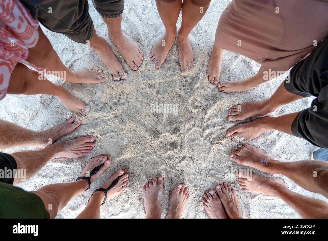 Viele weibliche und männliche Beine zusammen stehen auf Sand in der Nähe des Meer, Sommerferien Konzept. Draufsicht auf die Füße von Menschen oder eine Gruppe von Freunden auf der Beac Stockfoto