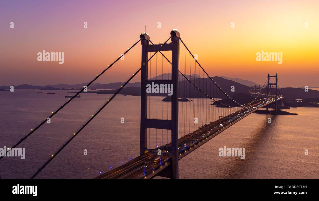 Die Tsing Ma Brücke, Hongkong, in der Dämmerung. Die riesige Hängebrücke, die sowohl den Straßen- als auch den Schienenverkehr befördert, beleuchtet bei Sonnenuntergang. Stockfoto