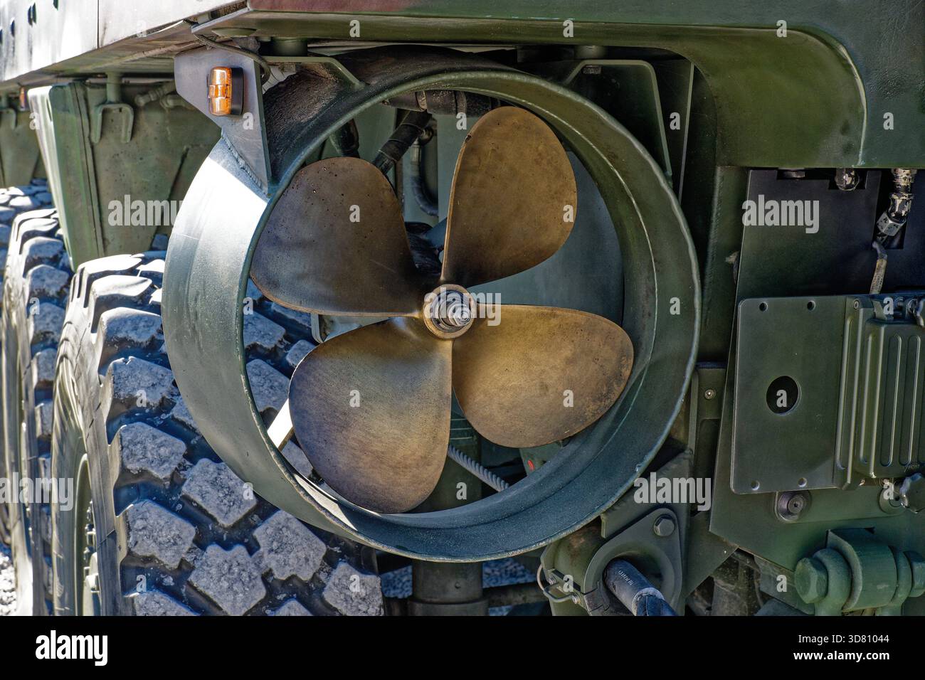 Nahaufnahme eines Propellers an einem amphibischen Militärfahrzeug mit robustem Reifenprofil und einem Teil der grünen Karosserie. Stockfoto