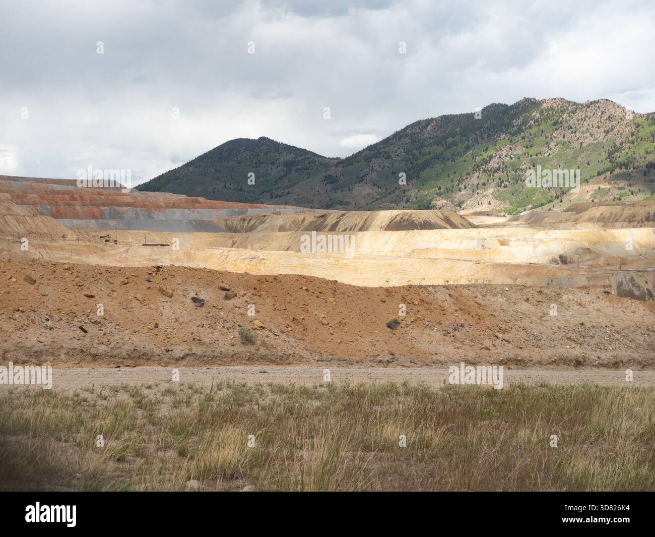 Berkeley Pit, eine offene Kupfermine in Butte, Montana, mit terrassierten Bergeflächen. Bewölkter Himmel oben. Stockfoto