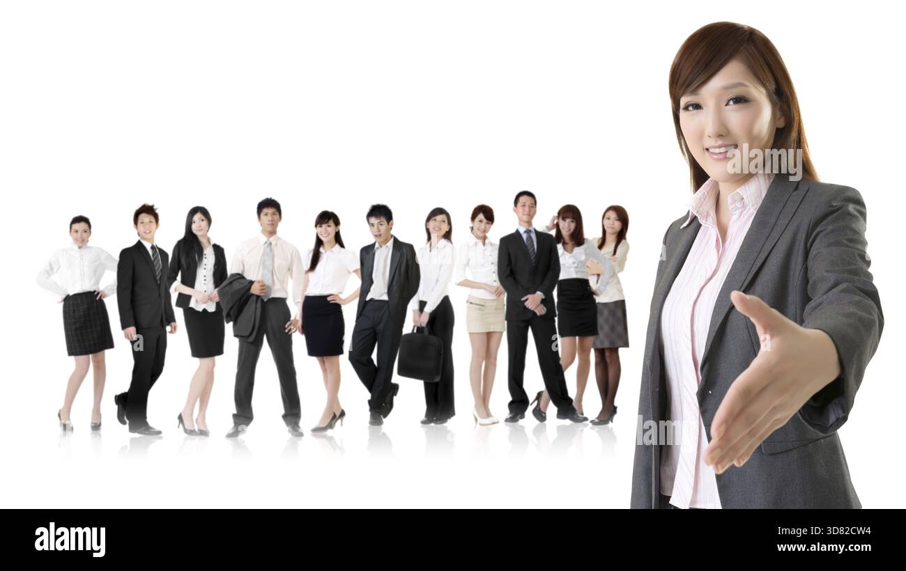Lächelnde Geschäftsführerin aus Asien macht einen Handschlag mit Ihnen vor ihrem Team isoliert auf weißem Hintergrund Stockfoto