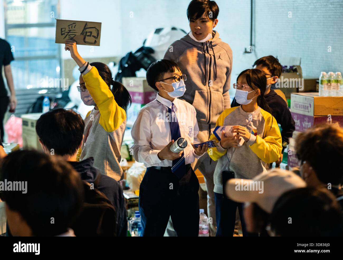 Teenager helfen den Bewohnern. Hongkong, China, 27. November 2025. Teenager beteiligen sich am Abend des 27. November 2025 an der Bereitstellung von heißem Wasser, Warmwasserpackungen und anderen Vorräten für die Bewohner in der Nähe des Brandortes in Hung Fuk Court, Tai Po, Hongkong. Quelle: Hou Yu/China News Service/Alamy Live News Stockfoto