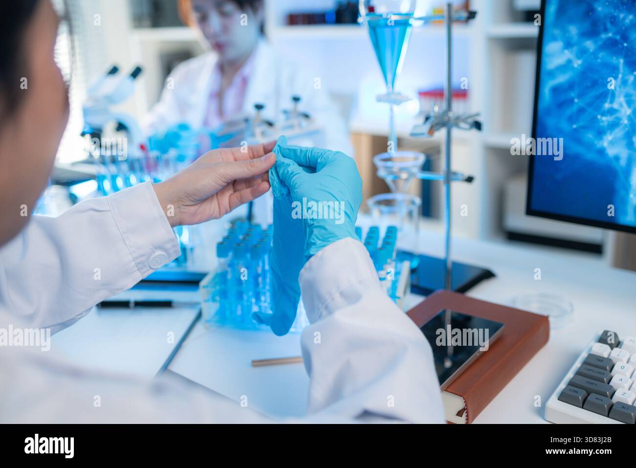 Ein modernes wissenschaftliches Labor mit organisierter Glaswaren, Reagenzgläsern gefüllt mit blauer Flüssigkeit und fortschrittlichen Forschungsgeräten auf einem sauberen weiß Stockfoto