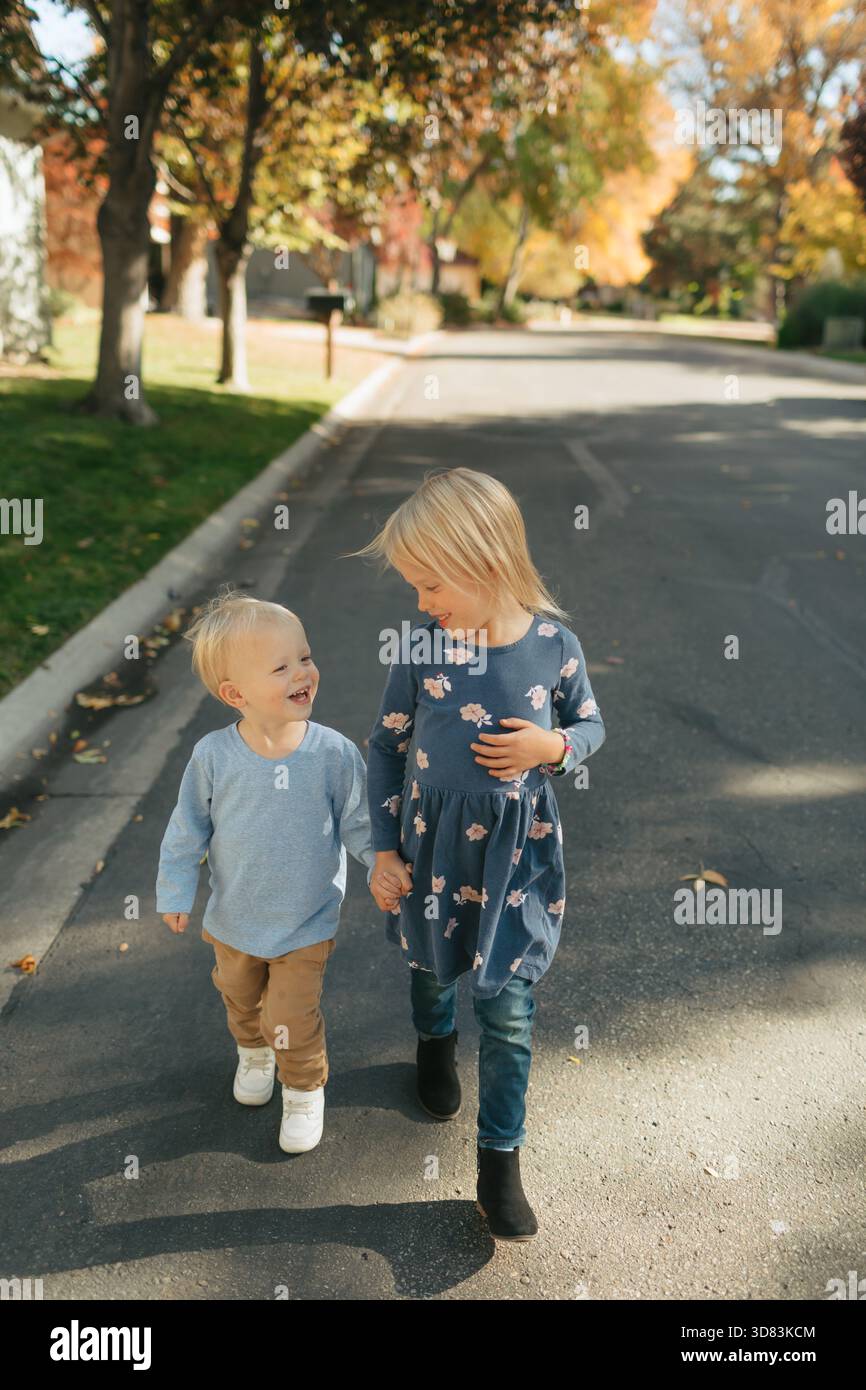 Glückliche Kinder Geschwister, die im Herbst im Freien die Hände halten Stockfoto