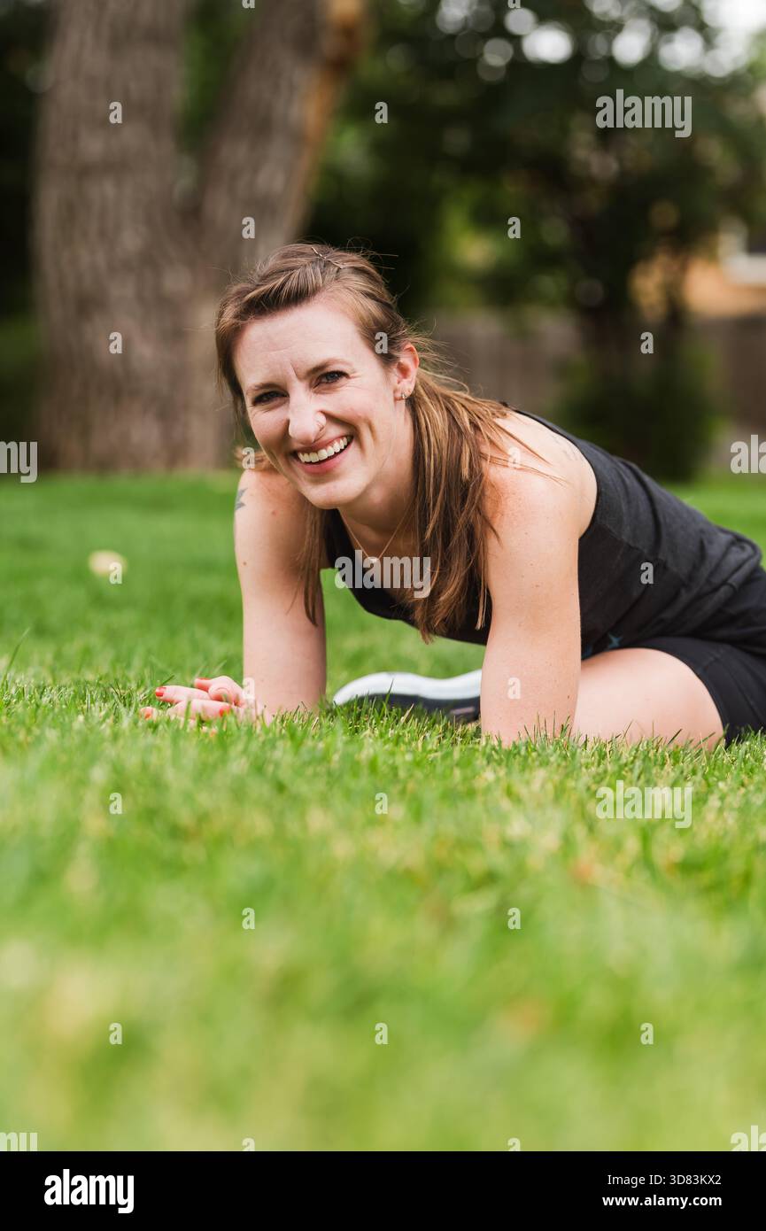 Brünette Frau lächelt vor einem Baum Stockfoto