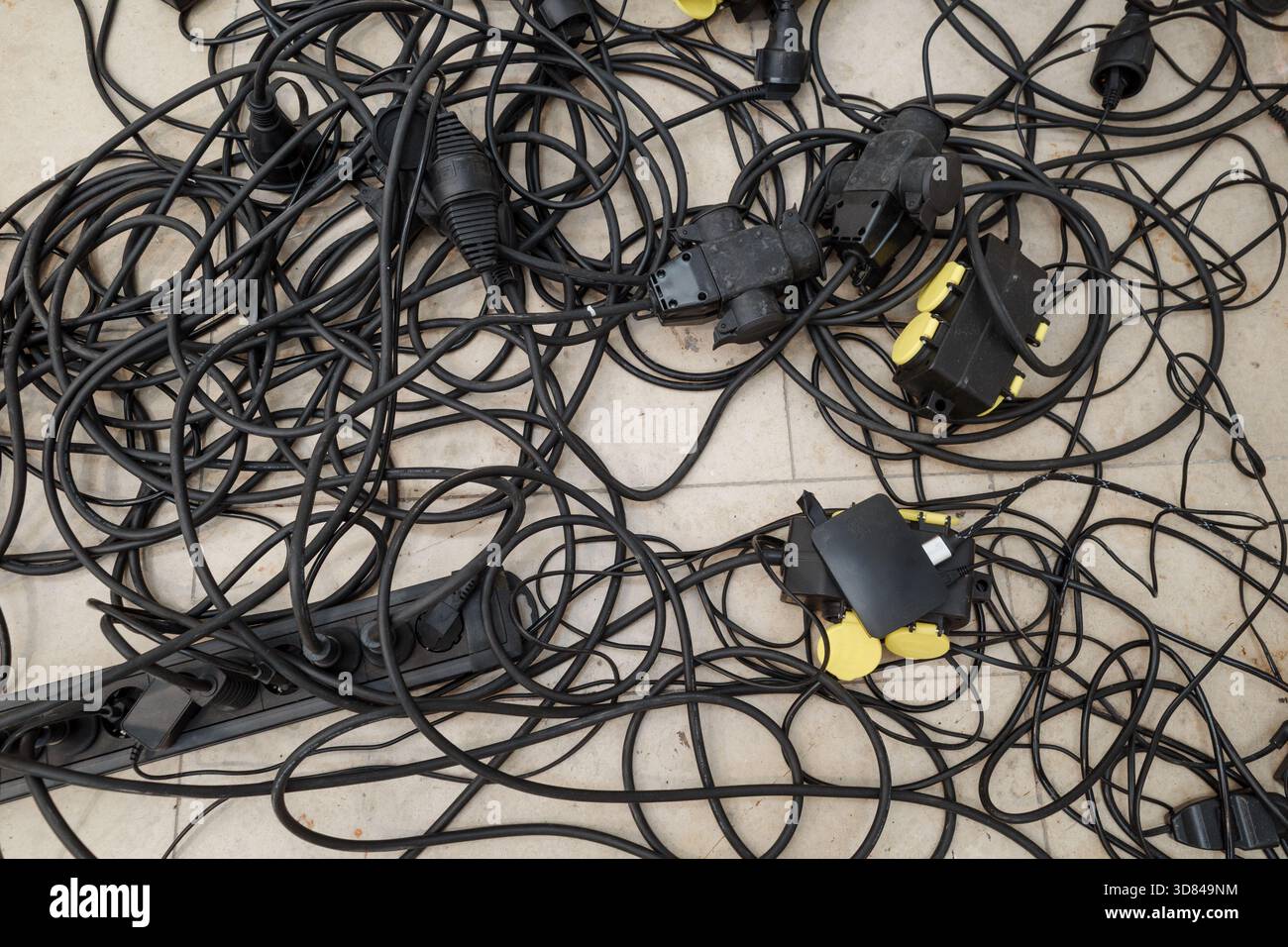 Chaotisches Chaos von verwickelten elektrischen Verlängerungskabeln und Steckdosenleisten Stockfoto