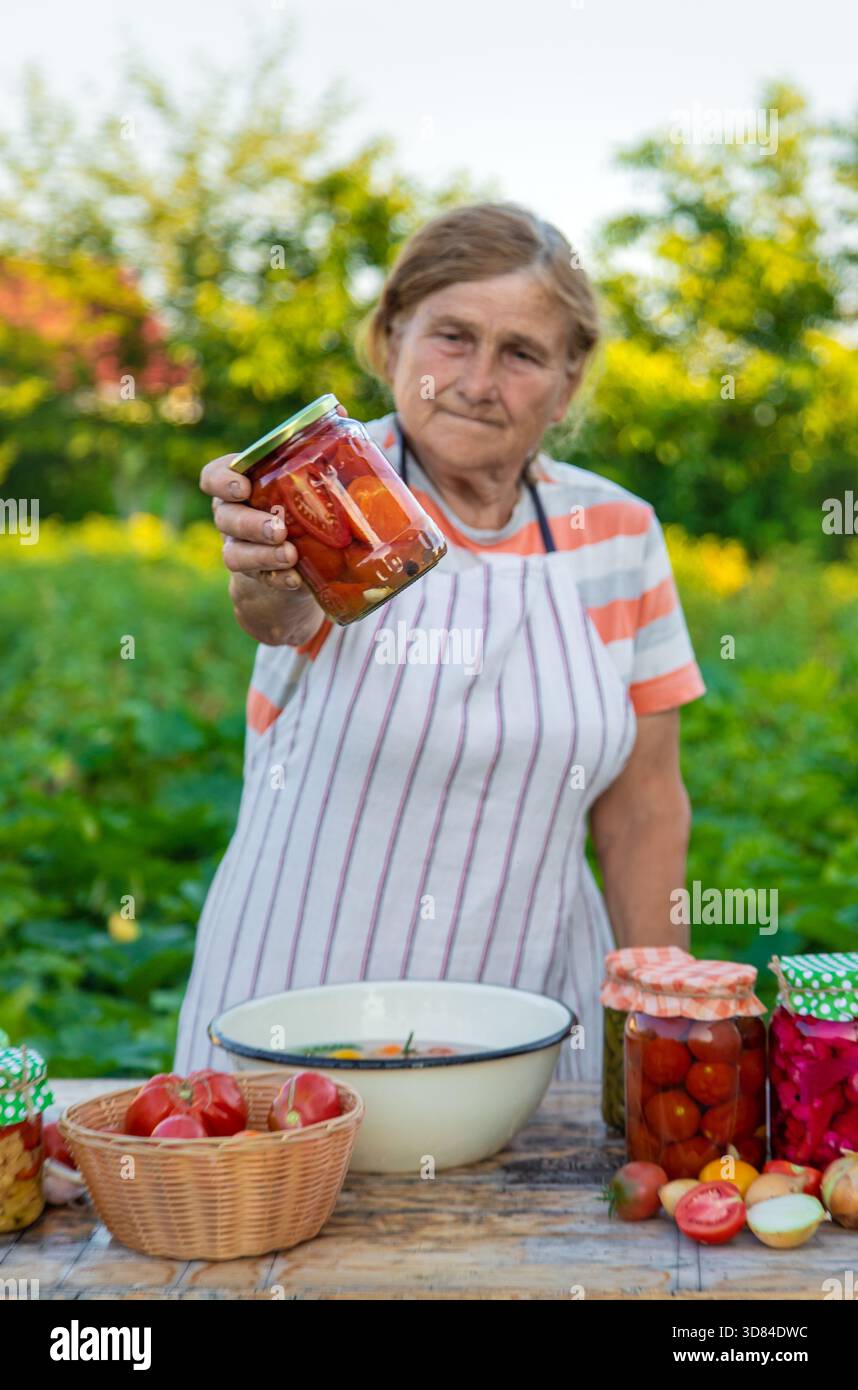 Ältere Frau, die Gemüse in Gläsern konservieren. Selektiver Fokus. Essen. Stockfoto