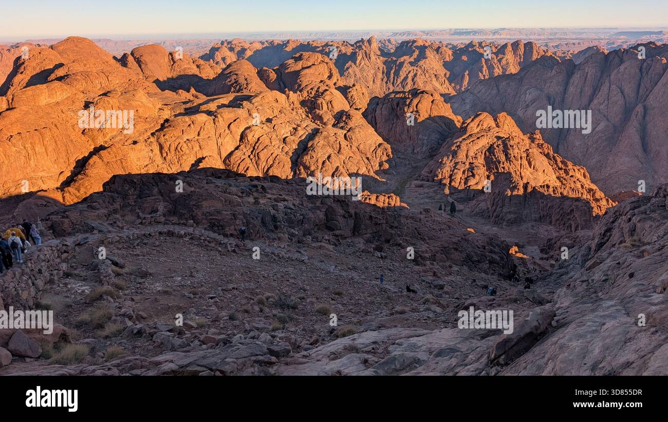 Sonnenlicht über den roten Bergen des Mount Sinai und die stille Schönheit der Wüstengipfel während des Aufstiegs zum Berg Moses Stockfoto