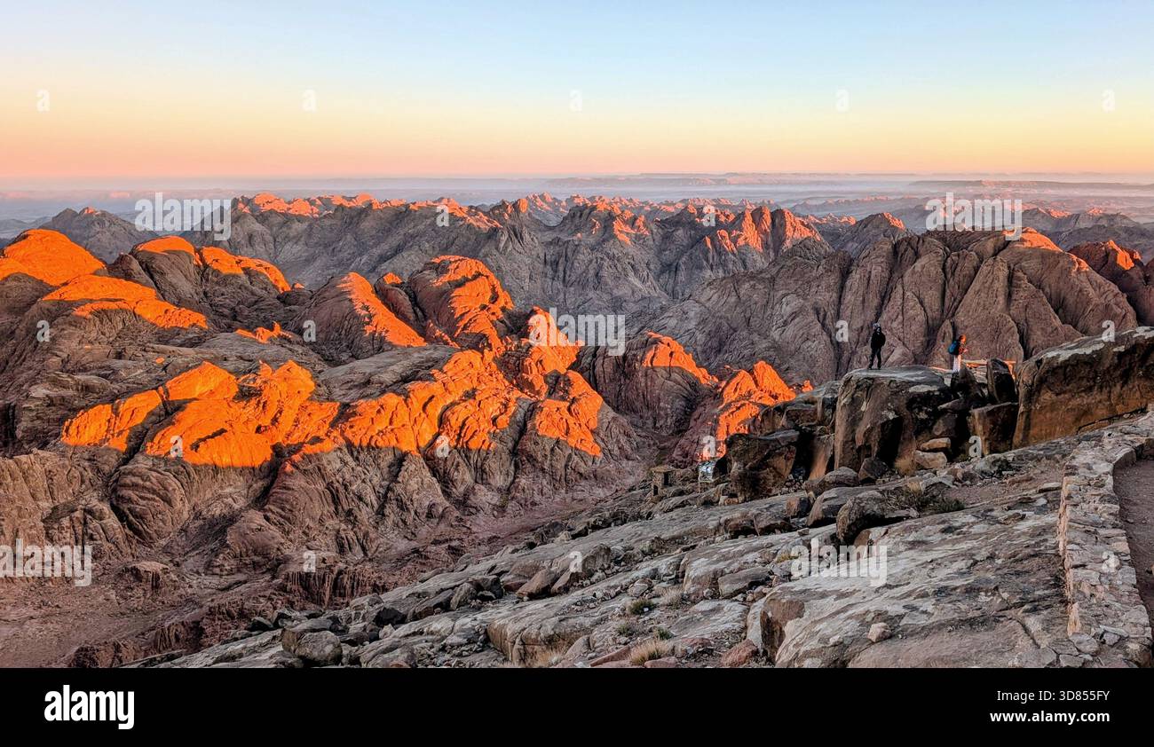 Sonnenlicht über den roten Bergen des Mount Sinai und die stille Schönheit der Wüstengipfel während des Aufstiegs zum Berg Moses Stockfoto