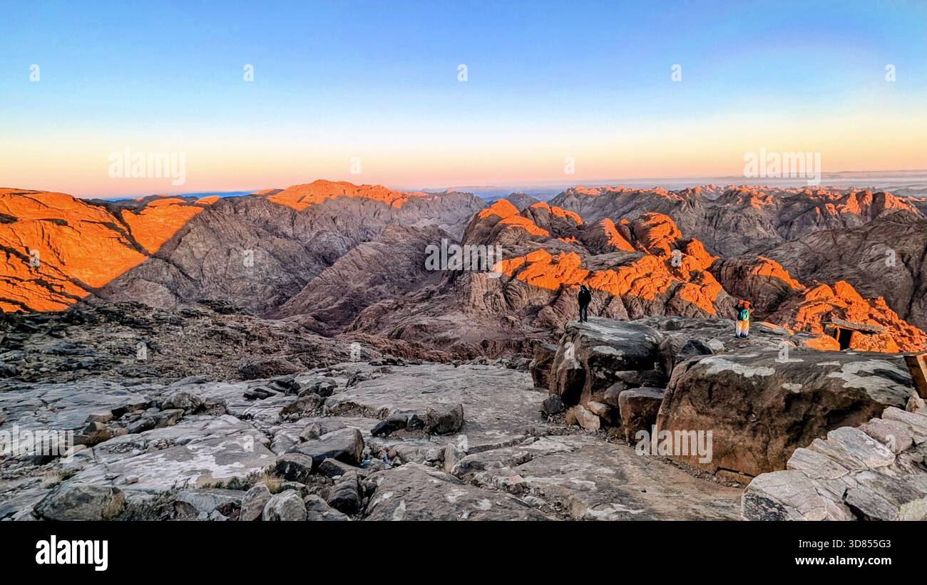 Sonnenlicht über den roten Bergen des Mount Sinai und die stille Schönheit der Wüstengipfel während des Aufstiegs zum Berg Moses Stockfoto