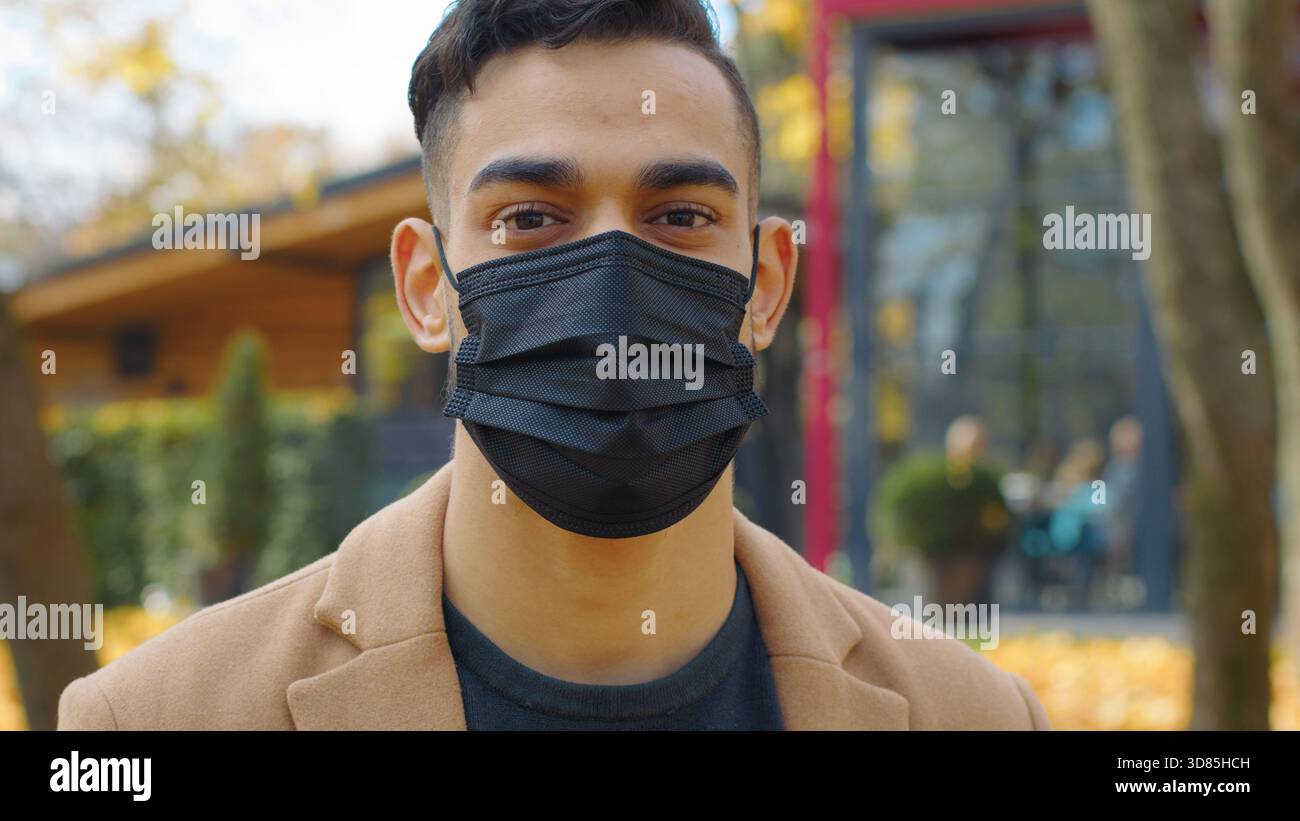 Close-up Hispanic Mann in Gesichtsmaske Blick auf Kamera Porträt Arabischer Mann in Stadt Herbstpark Indischer Mann posiert Pandemie covid19 krank Stockfoto