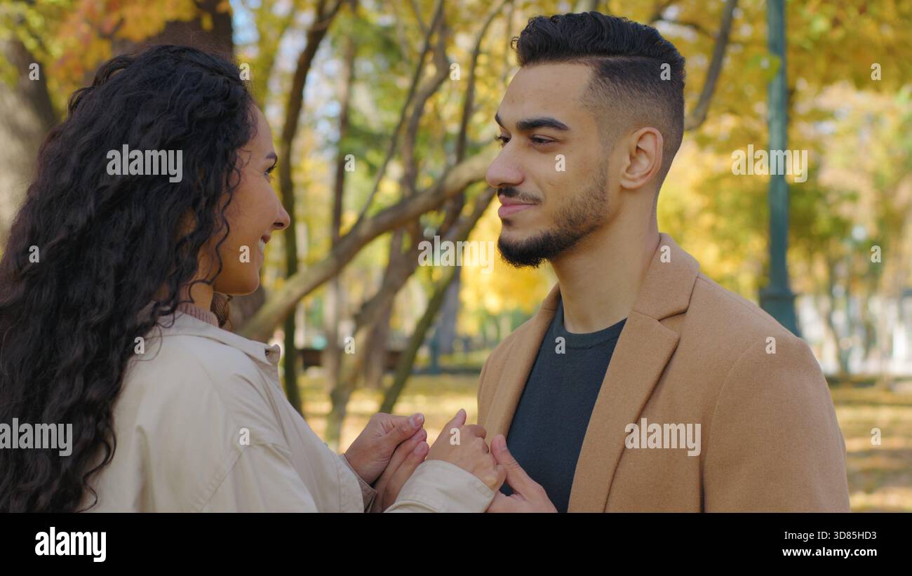 Hispanisches glückliches Paar spricht unbeschwert im Herbstpark multiethnische Familie kaukasische Frau spricht mit arabischem Mann in Stockfoto